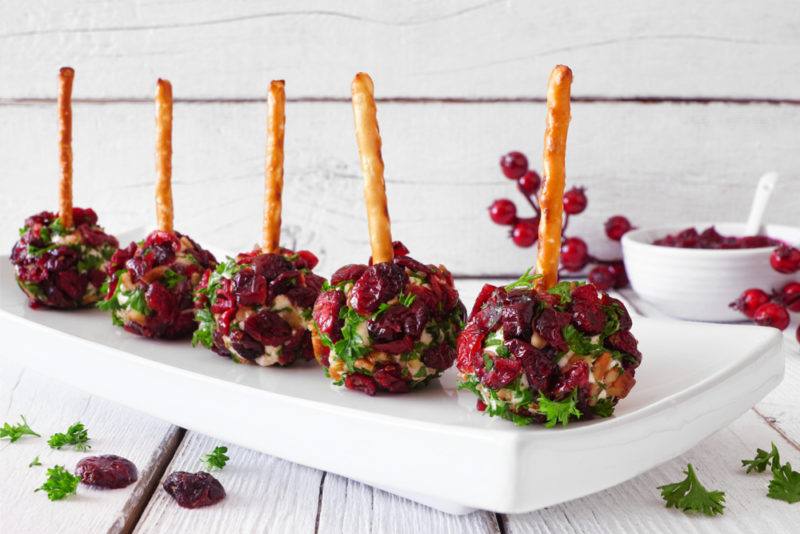 A white plate with mini cheese balls on pretzel sticks