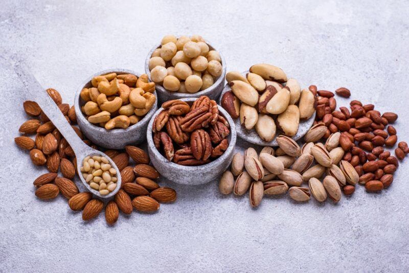 Various bowls containing nuts, including pecans, with some on the table as well