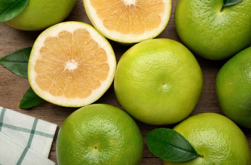 A selection of orange oroblanco fruits with one that's been cut in half