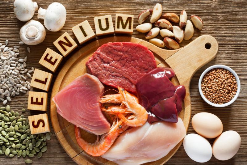 A brown wooden table with various selenium rich foods and the word selenium made from blocks