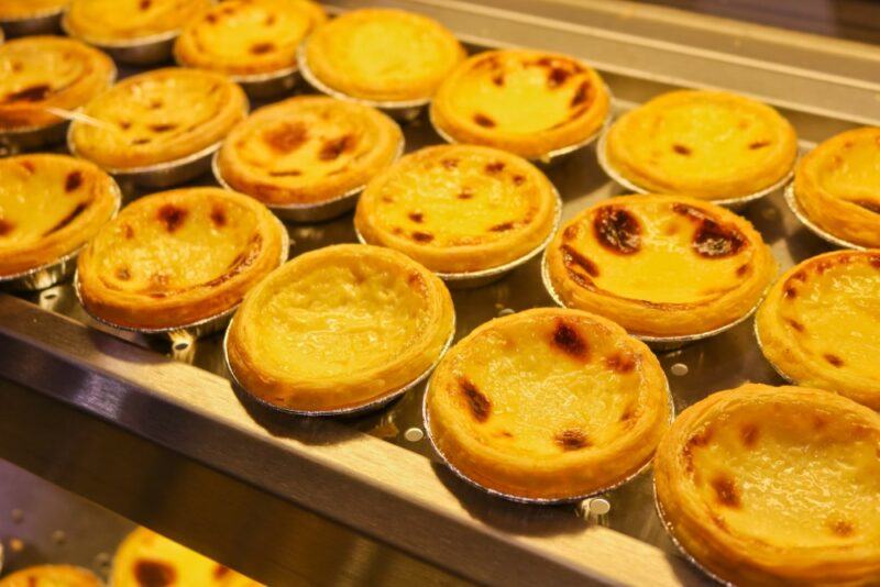 A wooden tray with a large number of small egg tarts