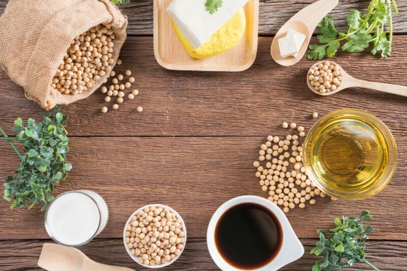 A wooden table with a selection of soy products, like soybeans and tofu