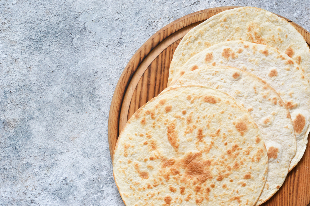 A round wooden board with tortillas