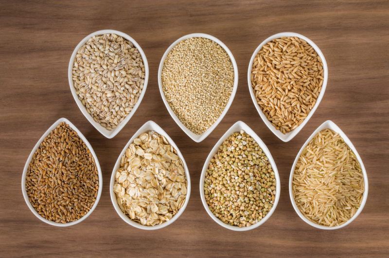 A variety of whole grains and pseudograins in white bowls