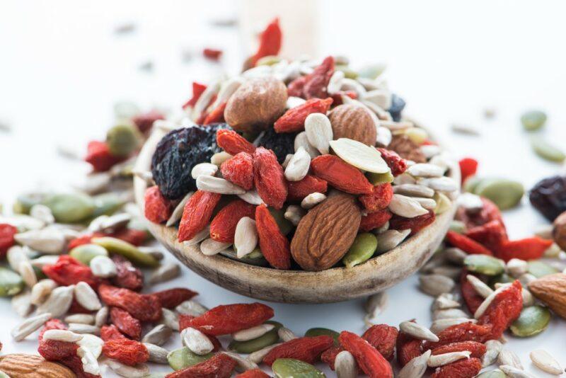 A shallow bowl containing trail mix, which includes almonds, seeds, and goji berries