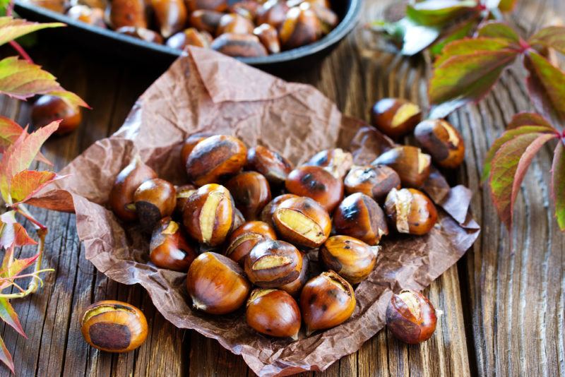 A sheet of crumpled paper with roasted chestnuts on a wooden table