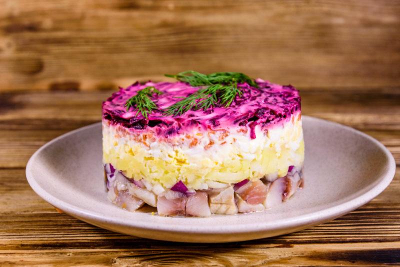 A shuba salad on a white plate with a layer of beets on top and herring at the bottom