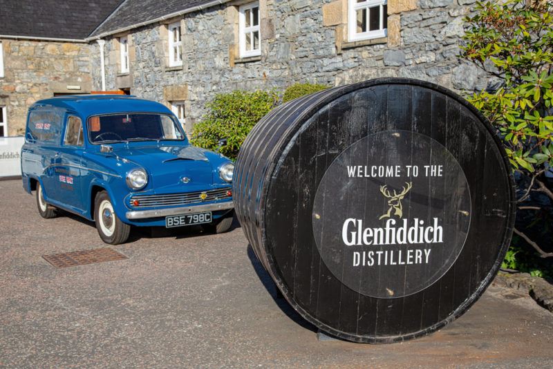 A sign for Glenfiddich whisky with a car behind it