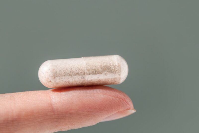 A finger with a single Metamucil tablet on it