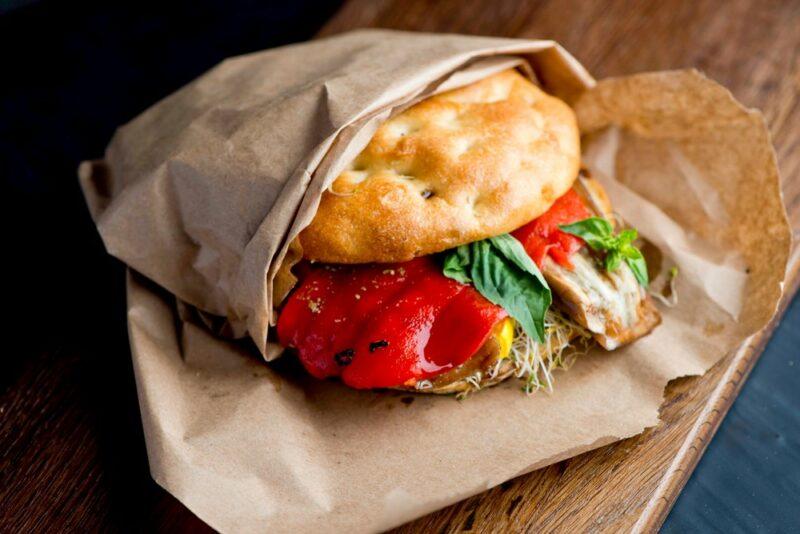 A fresh vegetable sandwich served on focaccia wrapped in paper