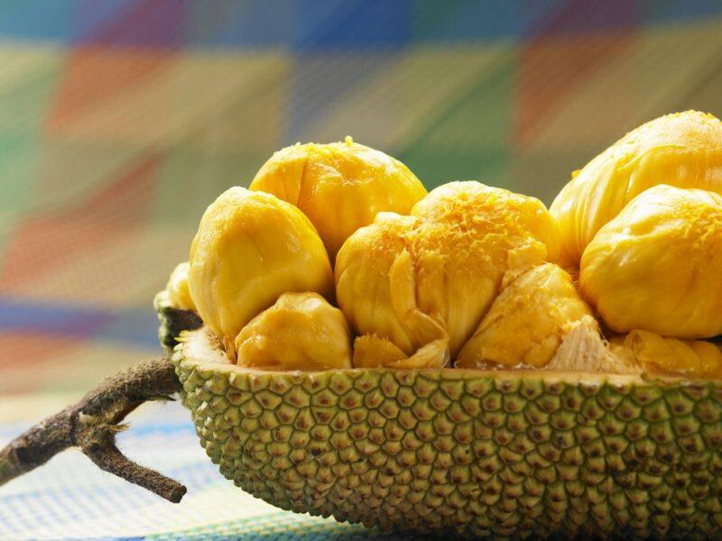 Half a cempedak fruit on a table with the yellow flesh showing clearly