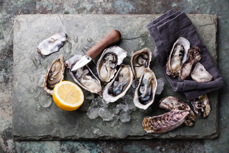 A slate board with fresh oysters and half of a lemon