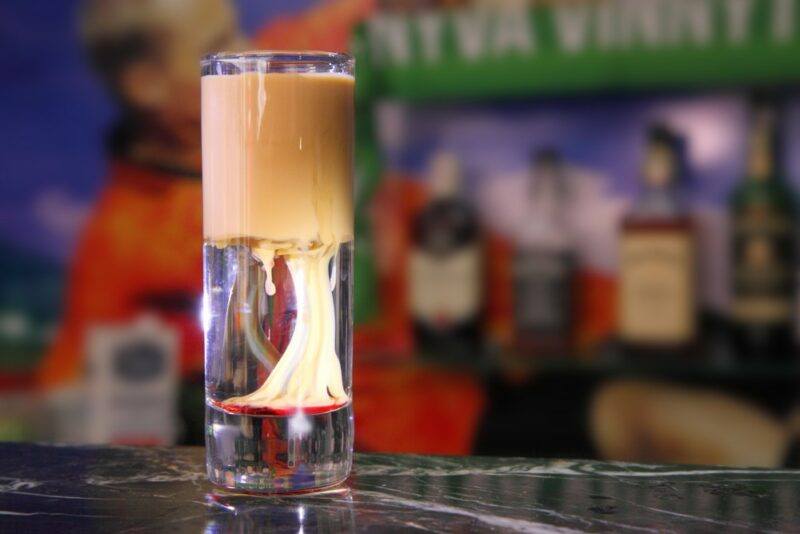 A shot glass with a slippery nipple shot on a bar