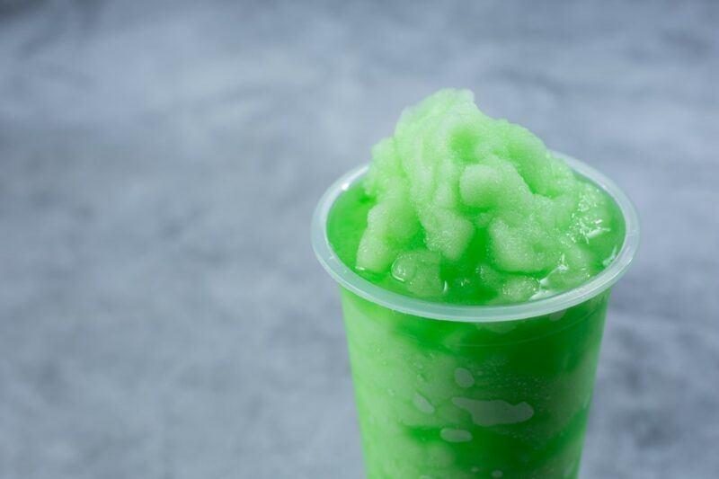 A glass containing a green slushie cocktail called green monster