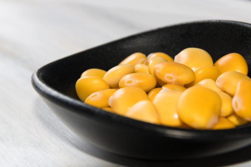 A small black bowl of yellow lupin beans