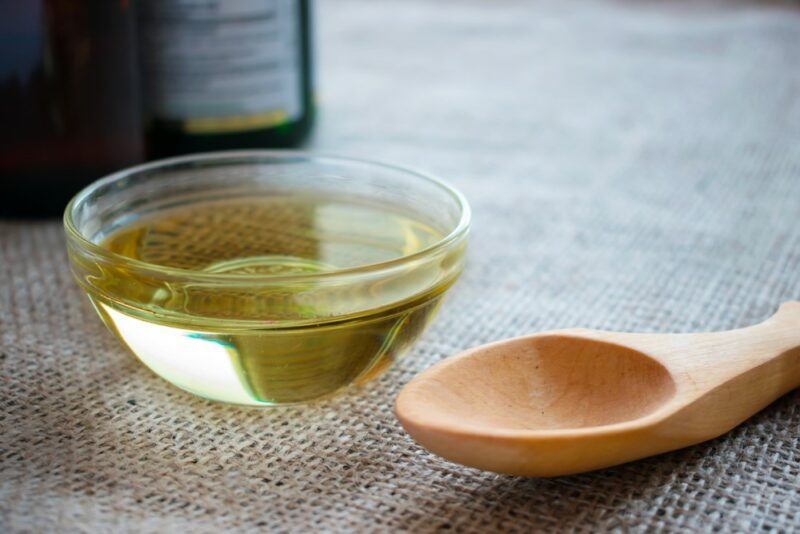 A small glass bowl of MCT oil next to a wooden spoon