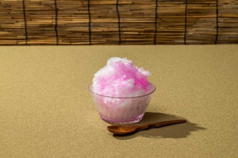 A table or bench with a small glass container of a birthday cake snow cone