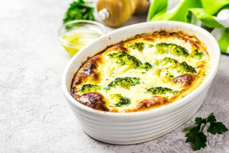 A white dish containing a broccoli mushroom ham and cheese bake