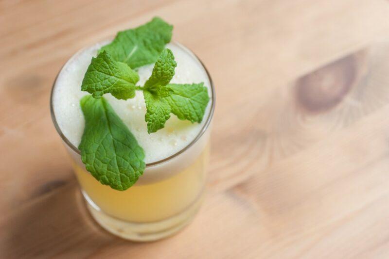 A wooden table with a snowball cocktail with a green garnish