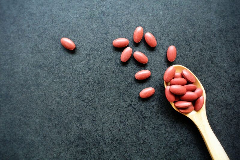 A spoonful of iron supplements spilling out onto a black table, looking at the best plant-based iron brands