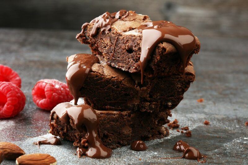 A stack of chocolate brownies on a table, drizzled with chocolate