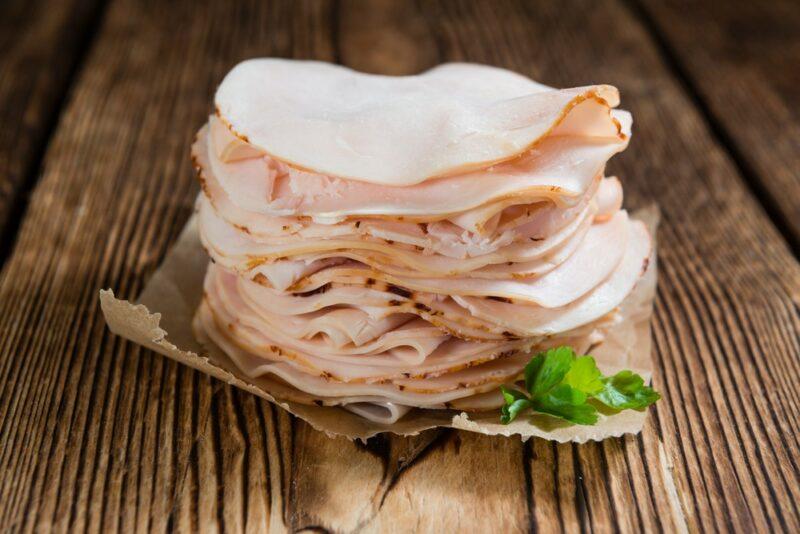 A stack of sliced turkey deli meat on a wooden table