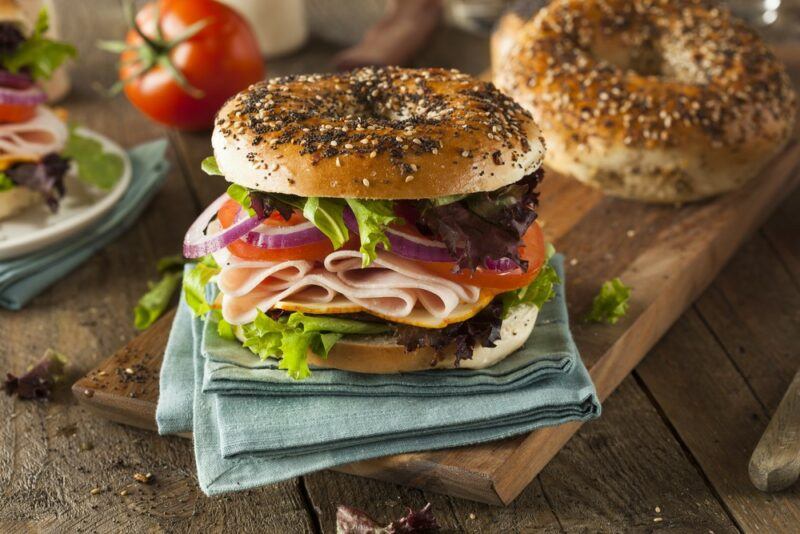 A stacked bagel sandwich, using ingredients like lettuce and ham