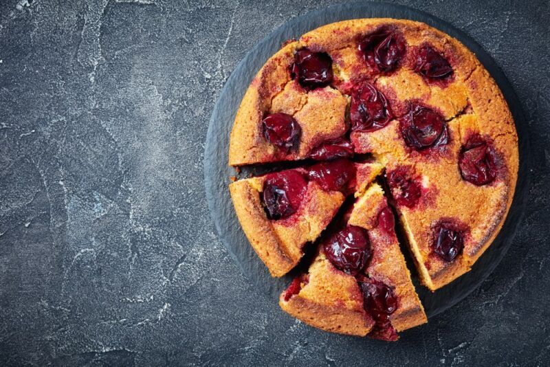 A gray table with a plum tart on it, where two slices have been cut into the tart