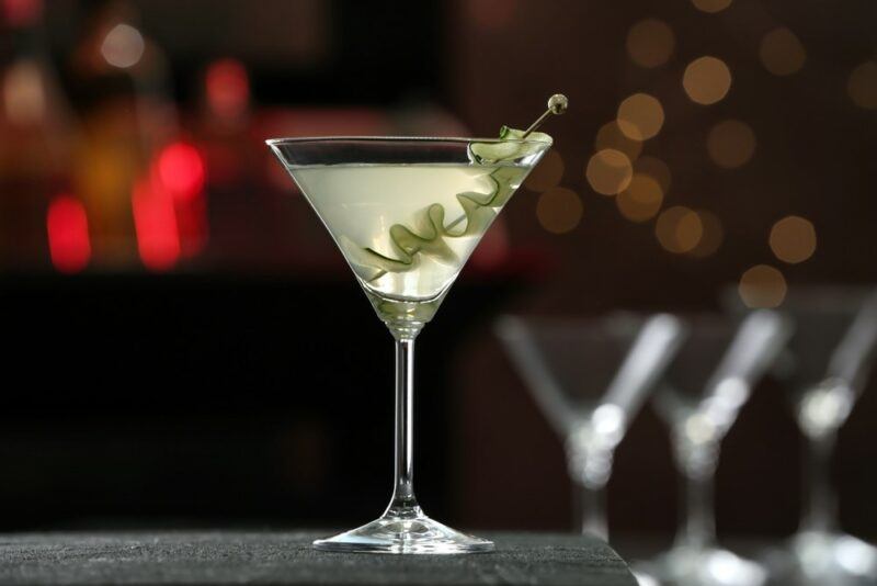 A glass of a tequila martini cocktail on a bar, with three empty cocktail glasses in the background