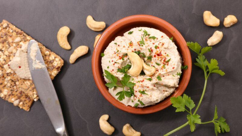 A terracotta bowl with homemade cashew cheese and various cashews