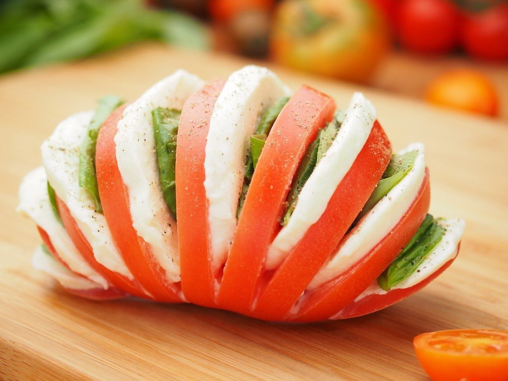 A tomato sandwich made with tomato, mozzarella cheese, and basil