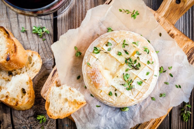 A top down image of camembert with herbs and crusty bread