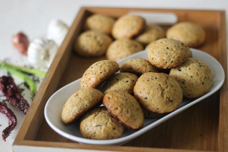 A wooden tray with a white plate. There are garlic cookies on the tray itself and also the plate