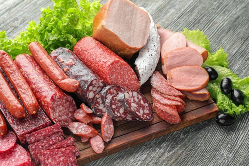 A wooden board with a selection of processed meats