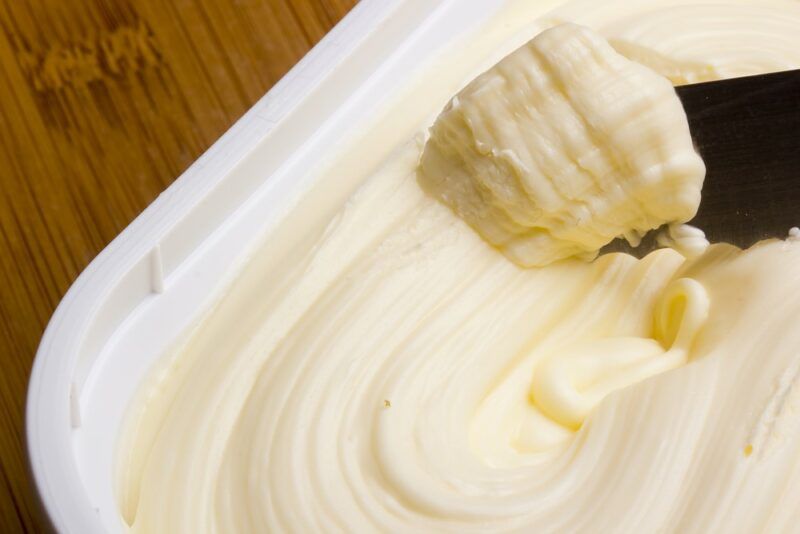 A tub of margarine with some being scooped out