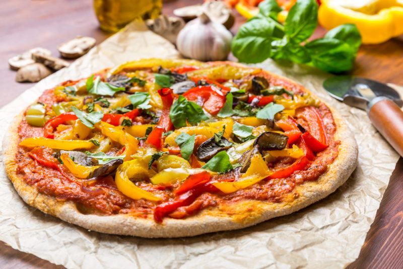 A vegan pizza with many vegetables on a cloth on a table