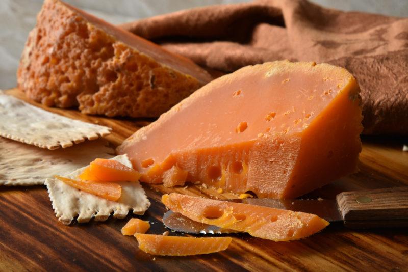 A wedge of gourmet Mimolette french cheese and artisan crackers