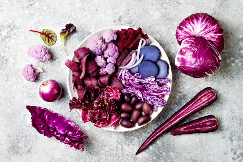 A white bowl with a variety of purple foods