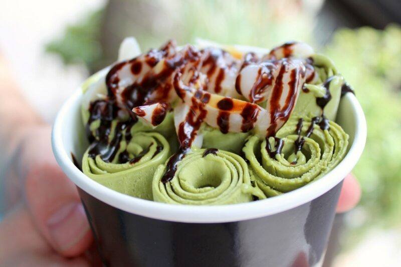 A black container with a white rim, containing Thai rolled ice cream, also called stir fry ice cream