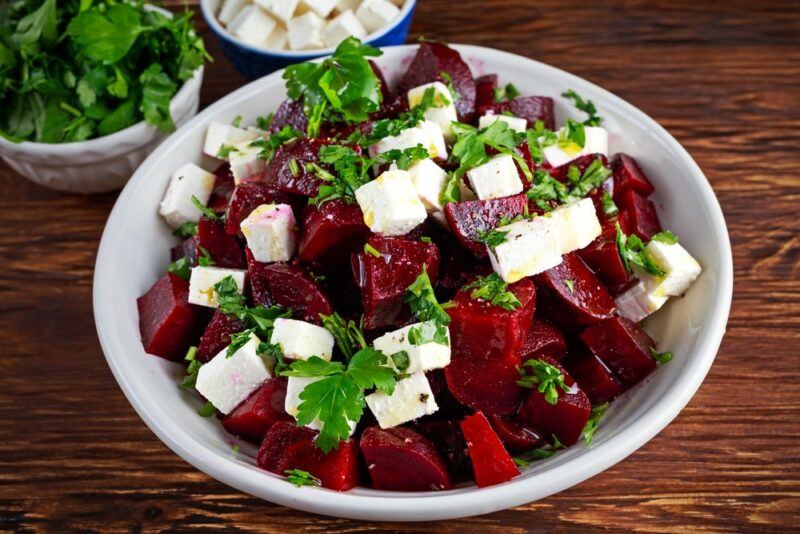 A white dish containing beet chunks, cheese, and parsley