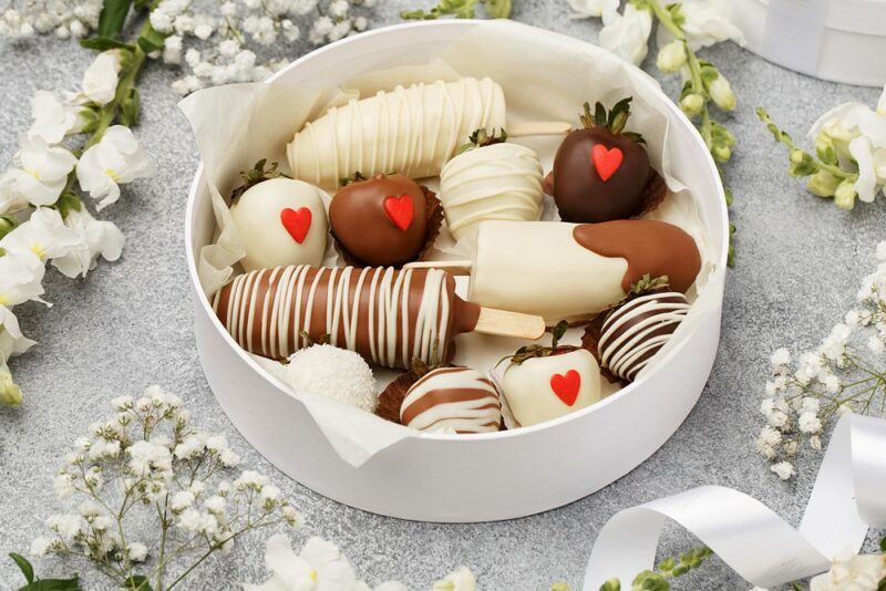 A white dish containing chocolate dipped fruit including strawberries and bananas