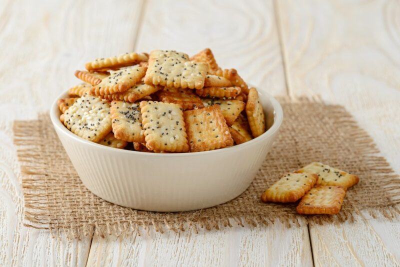 A small white bowl of herbed crackers on a piece of sacking