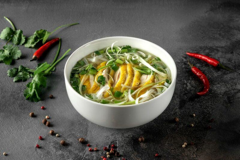 A white dish of fresh pho, including slices of lemon peel