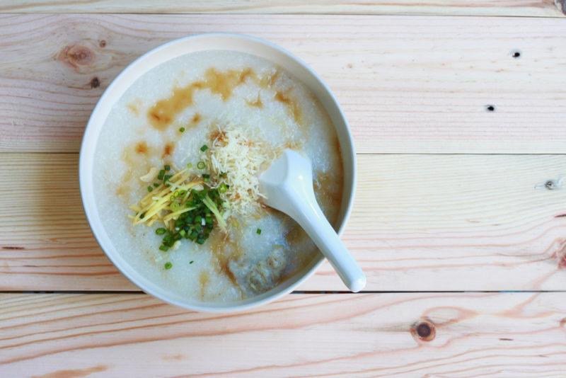 A white bowl of joke rice porridge with a spoon