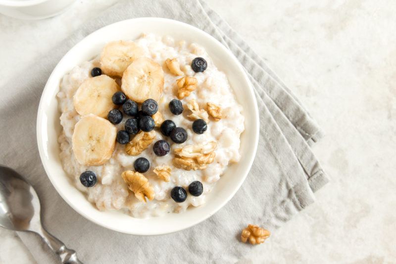 A white bowl of oatmeal with fruit