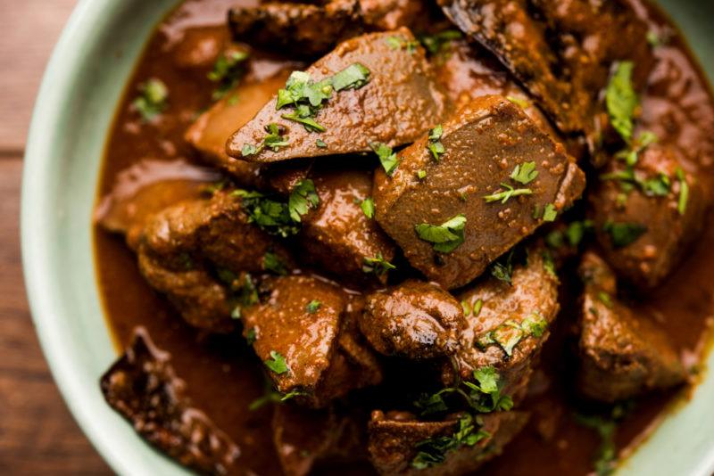 A white bowl with cooked lamb liver in gravy