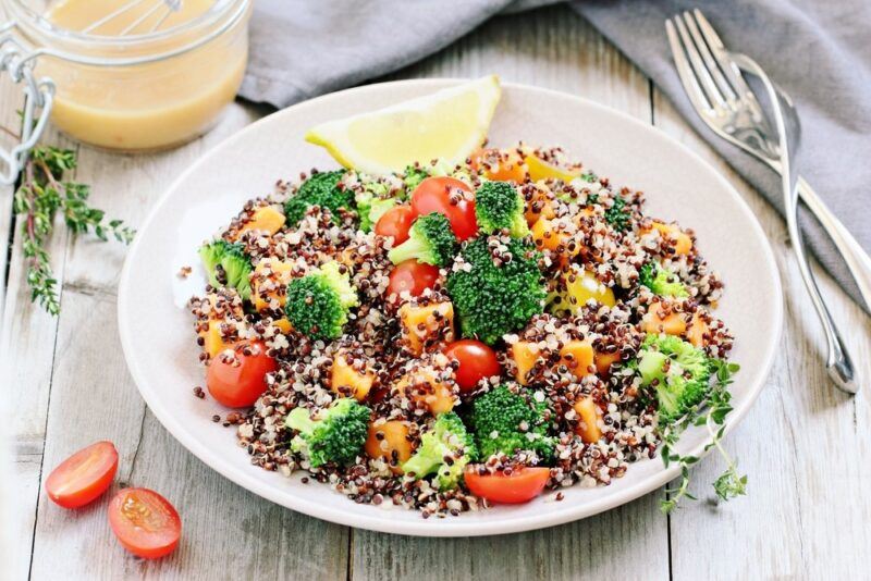 A white bowl of quinoa salad on a white table