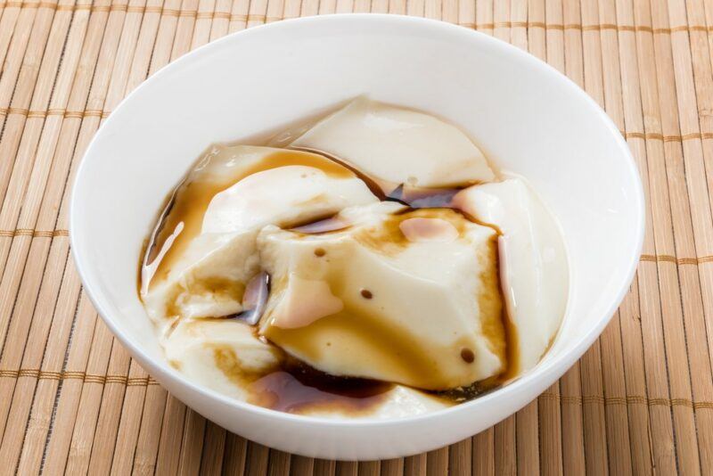 A white bowl containing soy milk pudding with a dark sugar sauce