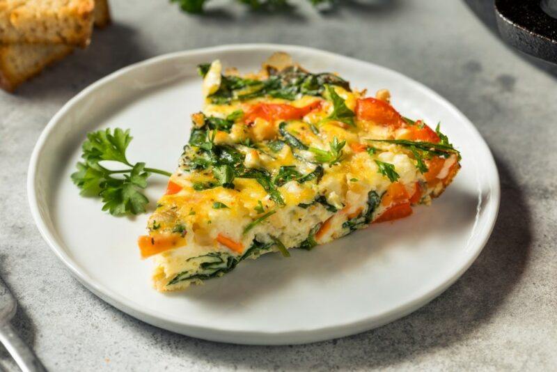 A large white plate with a single piece of frittata