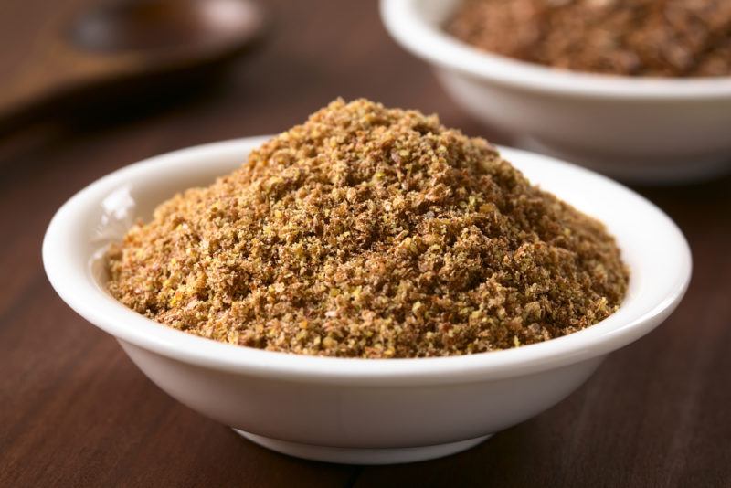 A bowl of ground flaxseeds with a second one in the background.